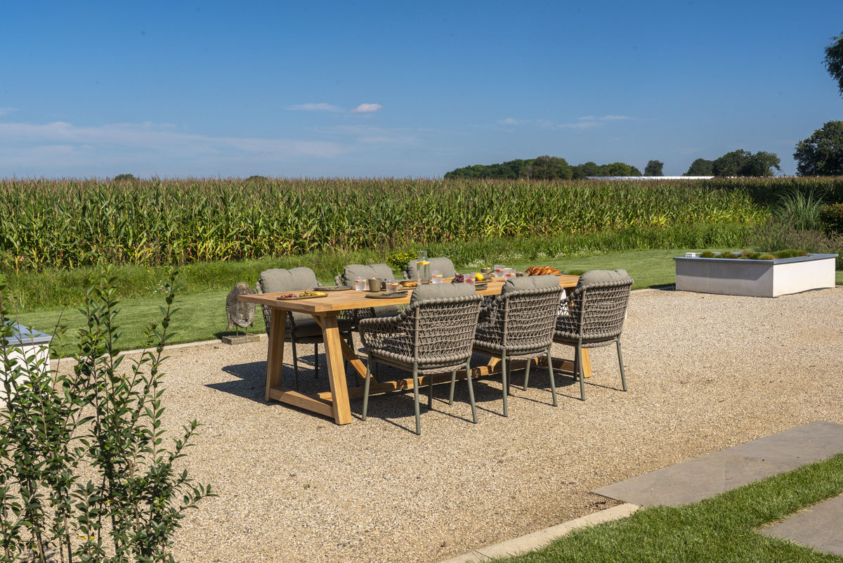 teak tuinmeubelen naast een aluminium loungeset op een terras